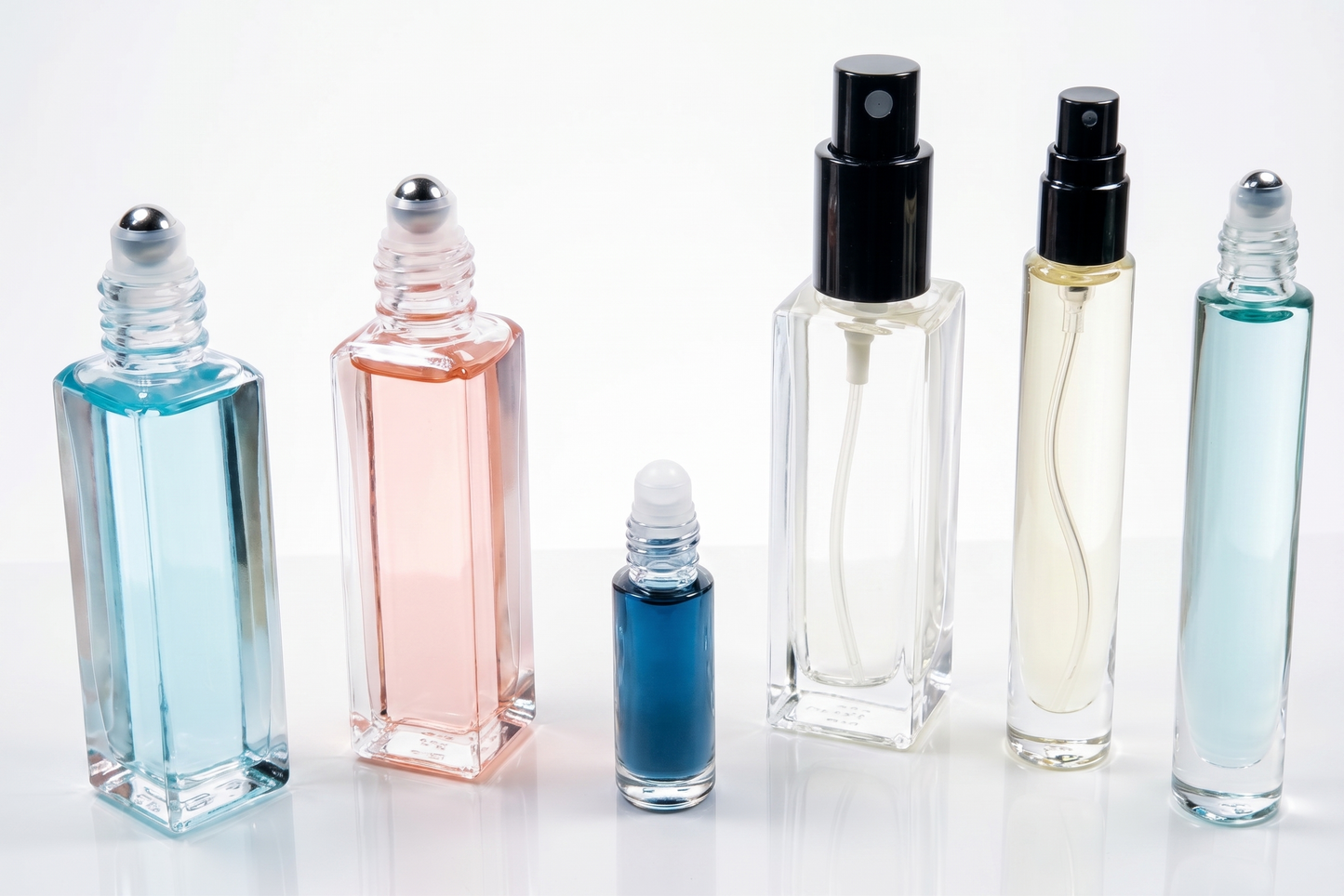 Five men's one ounce spray bottles with silver sprays and caps, filled with colorful eau de parfum, with a light blue sky background.
