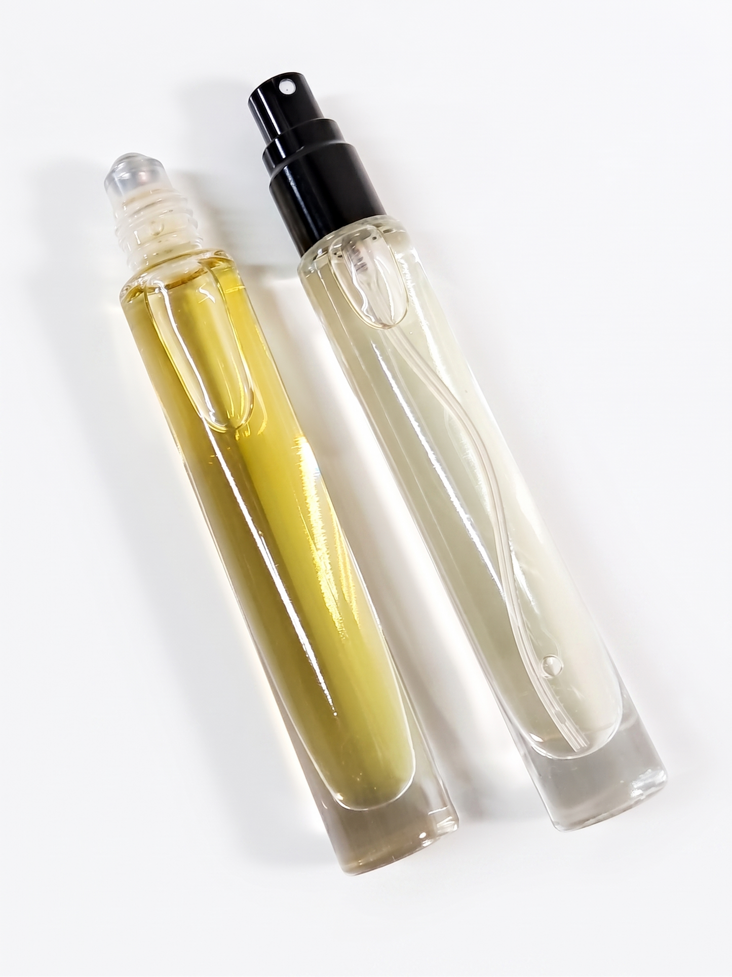 Two clear glass rollerball and spray perfume bottles with black caps, labeled Tobacco Leaf & Tonka by Comfort Crafts, on a clean white background.